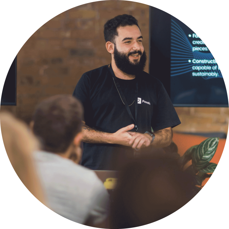 smiling man standing in front of a crowd giving a presentation